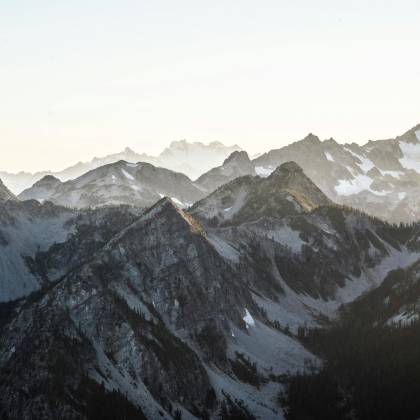 Breathtaking View Of Snow Covered Mountains During Dawn, Capturing Calm Nature And Winter Beauty.