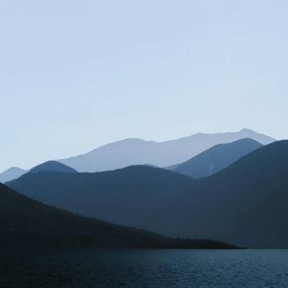 Serene Mountain And Lake View With Soft Silhouettes At Twilight.