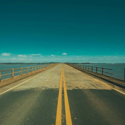 Long Bridge Extends Over Ocean Under Clear Blue Skies, Perfect For Travel And Adventure Inspiration.