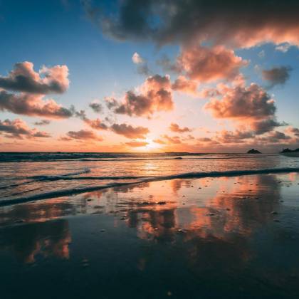 A Beautiful Sunrise Over Kailua Beach With Vibrant Clouds Reflected In The Calm Ocean Water.