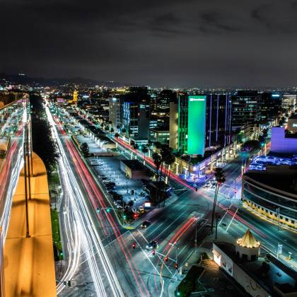 Dramatic Nighttime Cityscape Of Beverly Hills Showcasing Vibrant Light Trails And Illuminated Buildings.