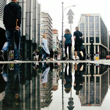 Reflective Street Scene In Poznań, Showcasing Modern Architecture And City Life.