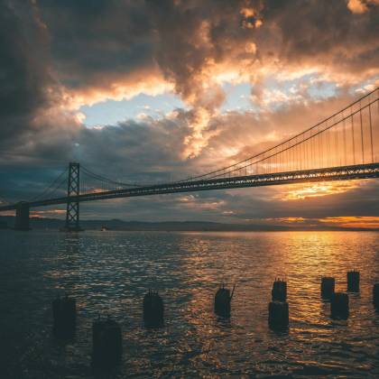 Stunning Sunset View Of The Bay Bridge In San Francisco Reflecting On Water.