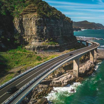 Breathtaking Aerial View Of Seacliff Bridge Over Rocky Coastline In Clifton, Australia On A Clear Sunny Day.