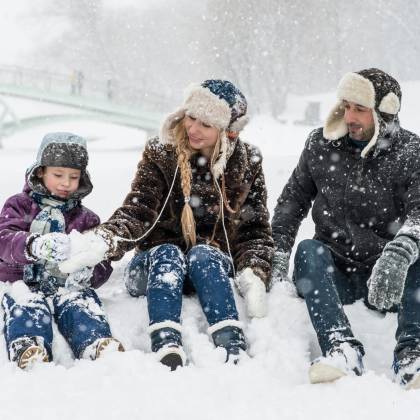 Happy Family Enjoying Playful Time In Snowy Winter Park, Capturing Joyful Moments In Nature.