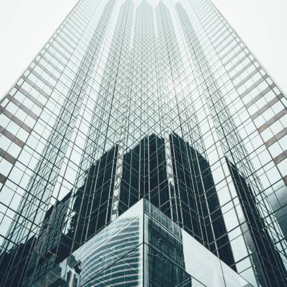 Striking Low Angle View Of A Modern Skyscraper With Reflective Glass Facade In A Cityscape.