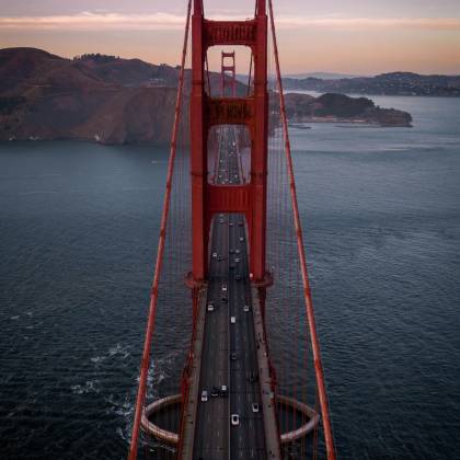 A Captivating Aerial View Of The Golden Gate Bridge At Twilight With Serene Ocean And Hills.