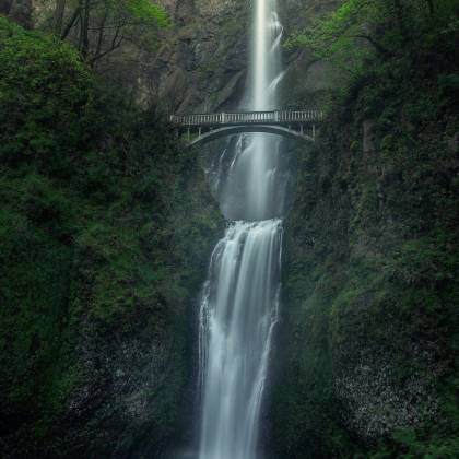 Stunning View Of A Cascading Waterfall With A Bridge In Oregon, Perfect For Nature Enthusiasts.