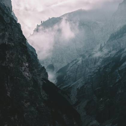 Misty And Dramatic Mountain Landscape Enveloped In Clouds, Showcasing Nature's Majestic Beauty.