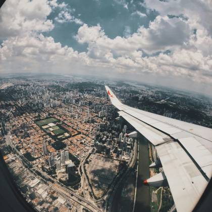 Aerial Cityscape Captured From Airplane Window With Skyline And Clouds, Showcasing Travel And Transportation.