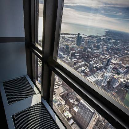 Stunning Aerial View Of Chicago Cityscape Through A Skyscraper Window With Lake Michigan In The Background.