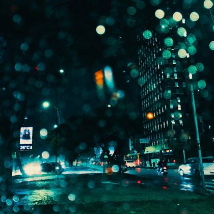 Dynamic Urban Night Scene With Illuminated Skyscrapers And Raindrops On Window.
