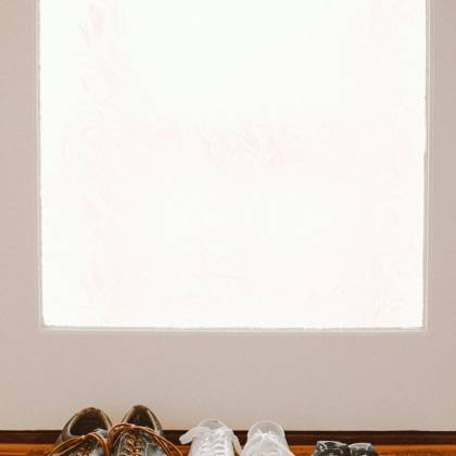 A Collection Of Family Shoes, Including Baby Booties, On A Welcoming Mat By The Door.