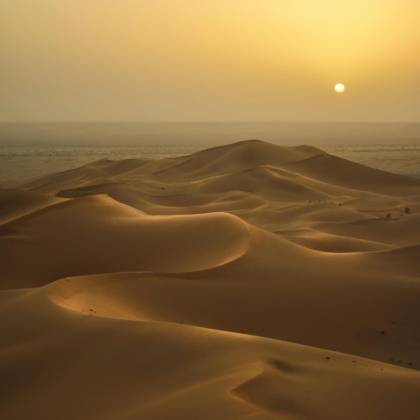 Peaceful Sunrise Illuminating The Vast Sand Dunes Of The Algerian Desert.