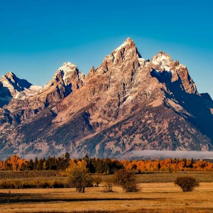 Breathtaking Autumn Landscape Of Grand Teton With Snow Capped Peaks And Colorful Trees.