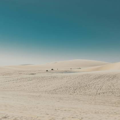 Vast Desert Landscape With Rolling Dunes And A Bright Blue Sky, Showcasing Nature's Untouched Beauty.