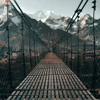 Breathtaking View Of A Suspension Bridge Leading To The Snowy Himalayan Mountains In Nepal.