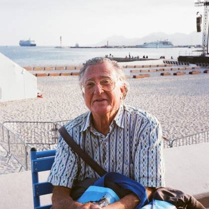 Senior Adult Enjoying A Sunny Day On A Beach With A Serene Sea Backdrop.