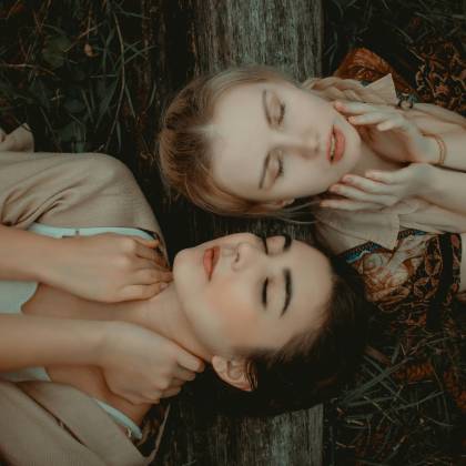 Two Women Relaxing Outdoors, Eyes Closed, Enjoying A Peaceful Moment In Nature.
