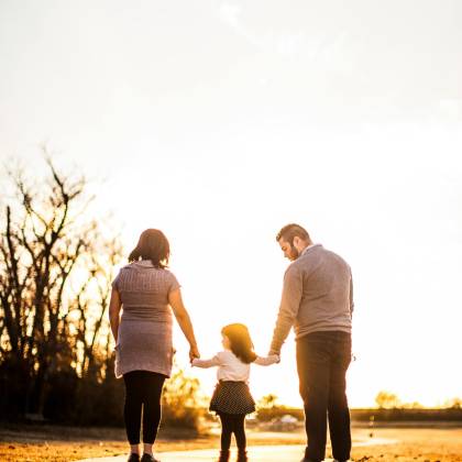 A Family Of Three Walks Hand In Hand At Sunset, Enjoying Togetherness And Warmth.