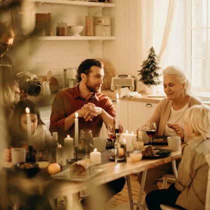 Family Enjoying A Warm Holiday Dinner Together With Candles And Laughter.
