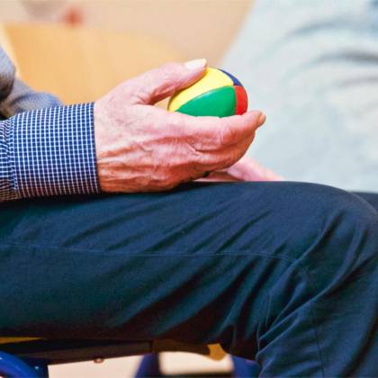 Elderly Man Holding A Colorful Therapy Ball Indoors, Promoting Relaxation And Health.