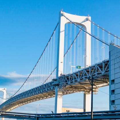 Stunning View Of Tokyo's Rainbow Bridge Under Clear Blue Skies.