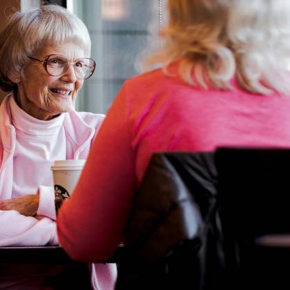 Senior Women Sharing A Joyful Conversation Over Coffee In A Cozy Indoor Setting.