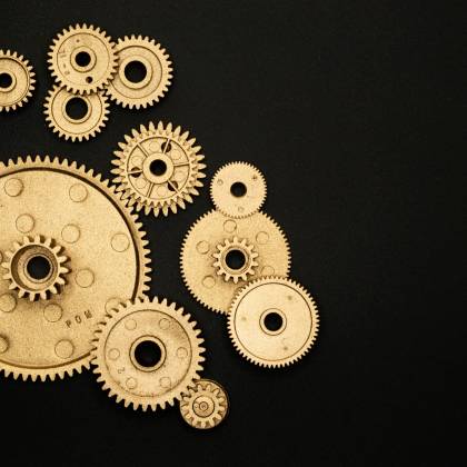 Close Up Of Gold Gears Arranged On A Black Backdrop, Symbolizing Teamwork And Technology.