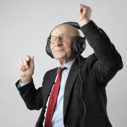 Senior Man Enjoying Music With Headphones, Expressing Happiness And Energy.