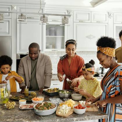 A Happy Family Gathers In The Kitchen To Prepare A Delicious Meal Together, Fostering Togetherness And Joy.