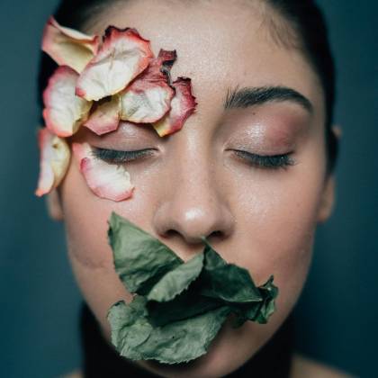 Artistic Portrait Of A Woman With Eyes Closed Adorned With Dried Petals And Leaves On Her Face.