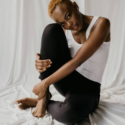 A Pensive Woman In A Minimalistic Setting, Seated On A Fabric Background In A Modern Portrait Style.
