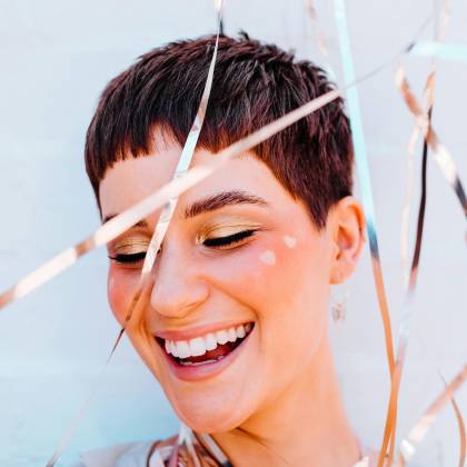 A Cheerful Woman With Short Hair Smiling Joyfully Surrounded By Vibrant Ribbons.