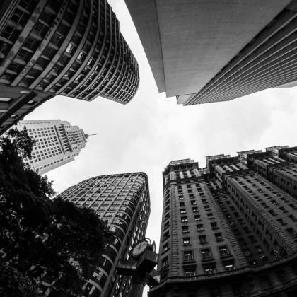 A Striking Black And White Photo Of Towering Skyscrapers Viewed From Below In An Urban Cityscape.