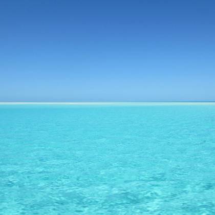 A Serene Blue Ocean With Crystal Clear Water Under A Vivid Blue Sky, Perfect For Relaxation.