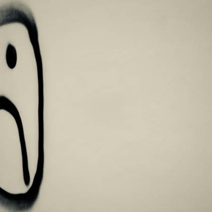 A Monochrome Photo Of A Sad Face Graffiti On A Wall, Symbolizing Urban Emotion.