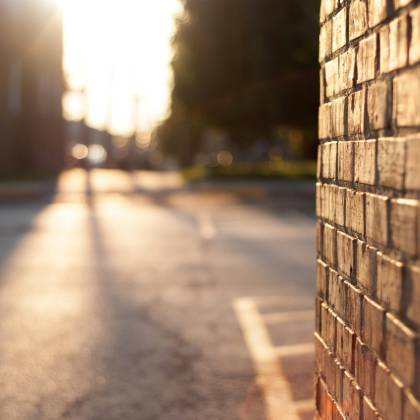 Close Up Of A Sunlit Brick Wall With Blurred Urban Street In The Background At Sunset.