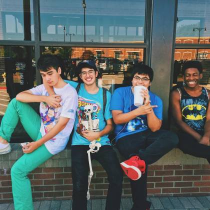 Group Of Teenage Friends Sitting Outdoors, Smiling And Having Fun Together.