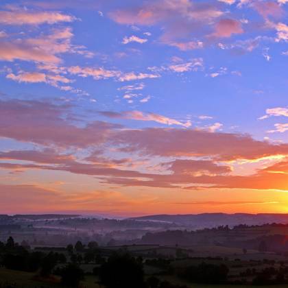 Stunning Sunrise Over Rolling Hills With Colorful Clouds And A Vivid Skyscape.